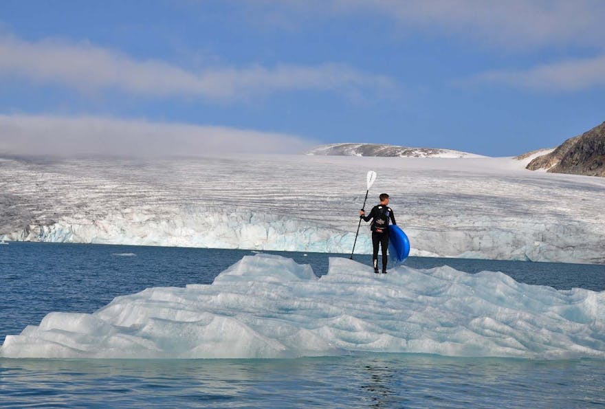 En kajakkpadler ser utover vannet og en smeltende isbre. Foto