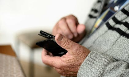 Eldre mann sjekker mobilbanken for saldo og regninger. Foto