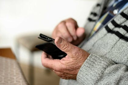 Eldre mann sjekker mobilbanken for saldo og regninger. Foto