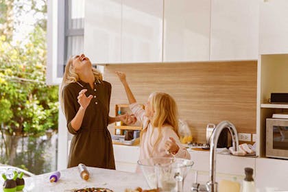 Mor og datter ler på kjøkkenet. Foto
