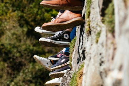 Ungdom som sitter på en mur med føttene dinglende utenfor kanten. Foto