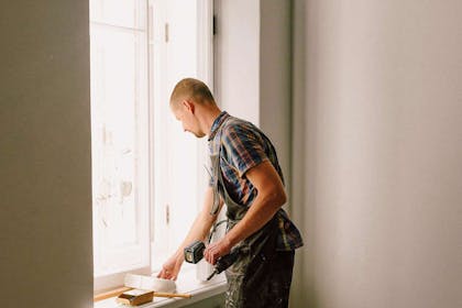 Mannlig snekker fikser et vindu. Foto