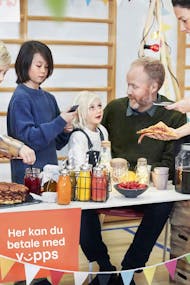 Barn og voksne tar betalt og kjøper vafler og smoothies i en gymsal. Foto